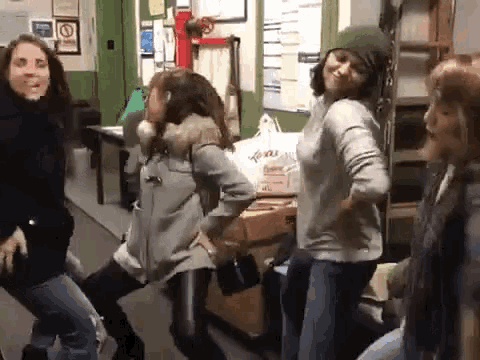 a group of women are dancing together in a room with a no smoking sign on the wall