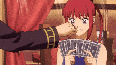 a girl with red hair is holding a bunch of playing cards in her hands