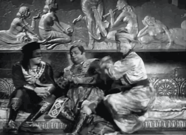 a black and white photo of three men sitting in front of a sculpture