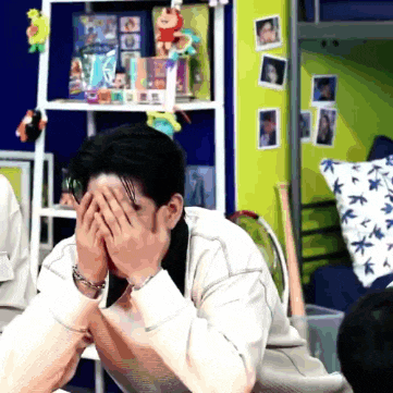 a man is covering his face with his hands in a room