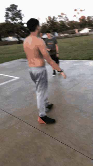 a man without a shirt is standing on a concrete floor