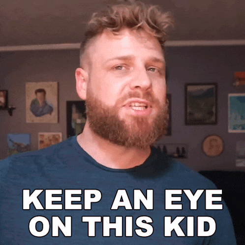 a man with a beard is wearing a blue shirt and says keep an eye on this kid