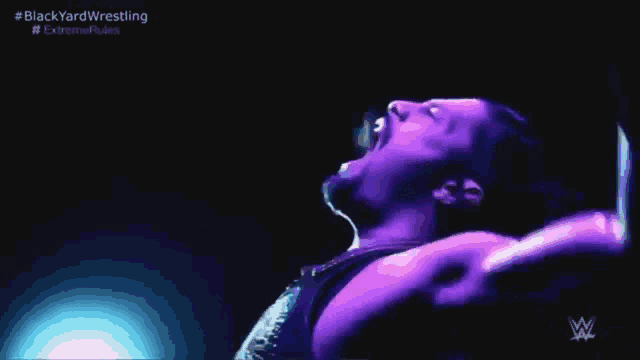a wrestler is laying on the ground with his arms outstretched in a dark room .