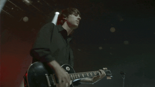 a man in a black shirt is playing a guitar