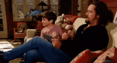 a man and a boy sit on a couch with a peace sign shirt on