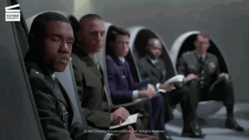 a group of men are sitting in a row with a columbia pictures logo in the background