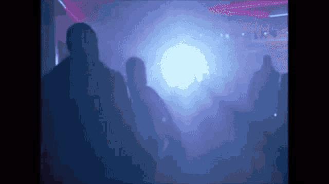 a group of people are walking in a dark room with purple lights