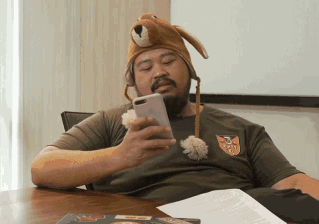 a man wearing a teddy bear hat is looking at his cell phone