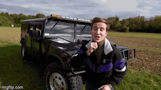 a man in a purple and black jacket is standing in front of a black jeep