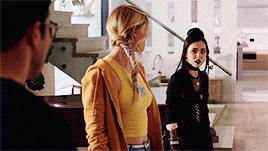 a woman in a yellow tank top stands next to a woman in a black jacket