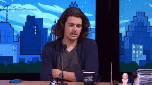 a man sitting at a table with a cup that says on the spot on it