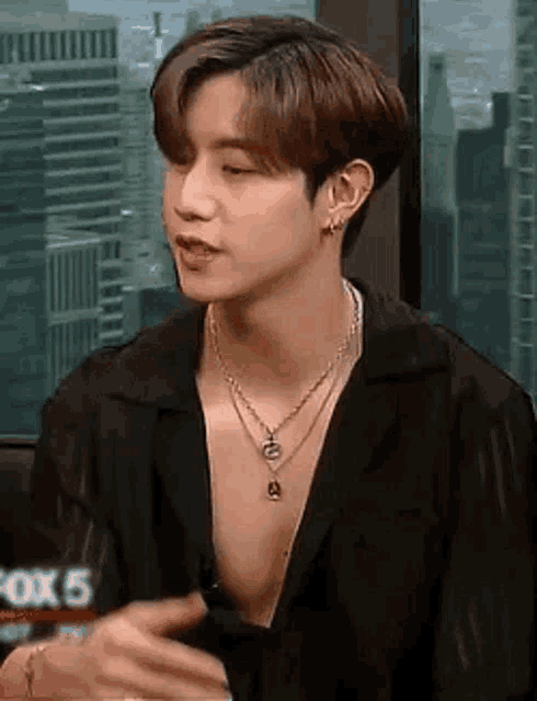 a close up of a person wearing a necklace and a black shirt .