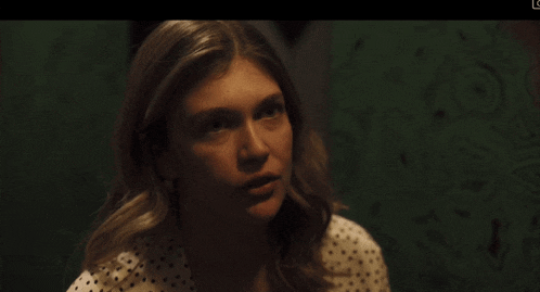 a woman in a white polka dot shirt is looking at a man