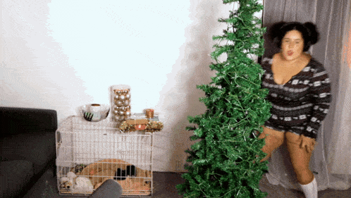a woman standing next to a christmas tree in a room