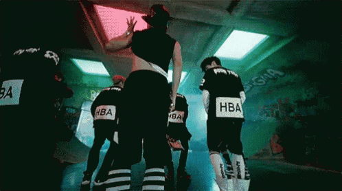 a group of people wearing hba shirts are standing in a dark room