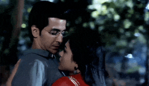 a man and a woman are hugging each other in a park .