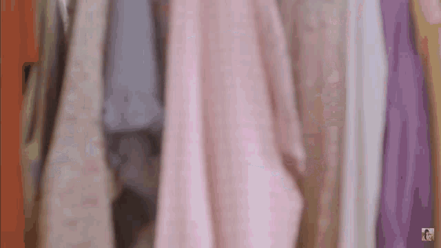 a woman is standing in a closet filled with clothes hanging on a rack .