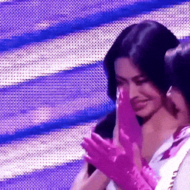 a woman wearing pink gloves is clapping with a man