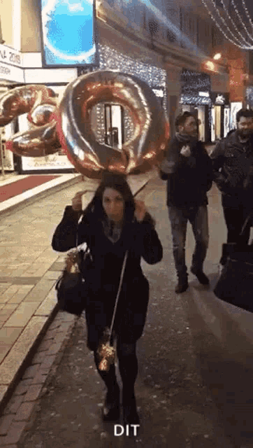 a woman is walking down the street holding a balloon that says dit on it