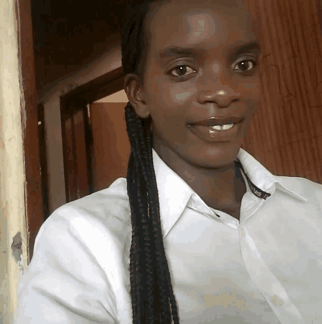 a woman with braids is wearing a white shirt and smiling for the camera