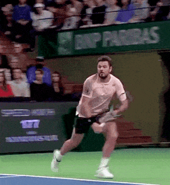 a man is running on a tennis court in front of a bnp paribas banner