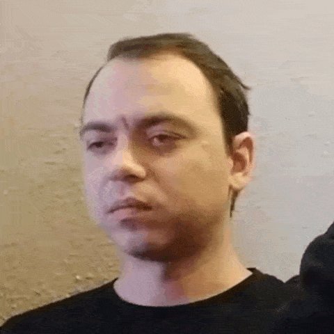 a man with a bald head and a black shirt is looking at the camera .