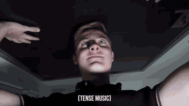 a young man is looking up at the ceiling and the words [ tense music ] are above him