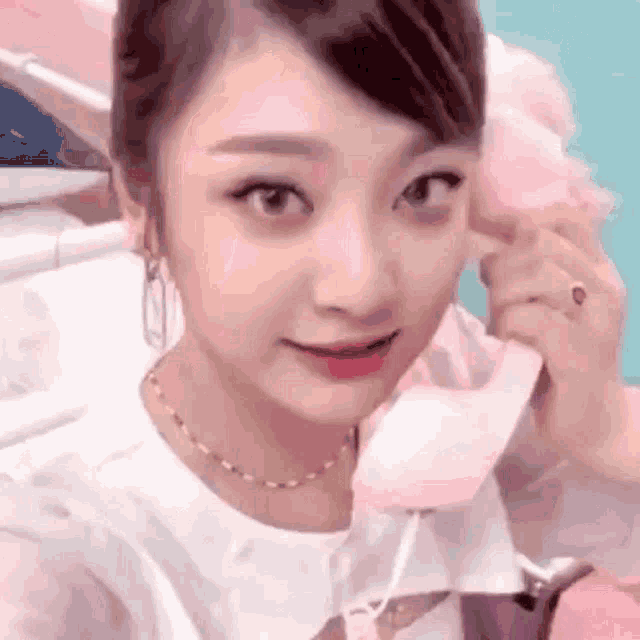 a close up of a woman holding a pink cotton candy in her hand .