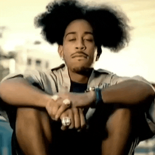 a man with curly hair is sitting with his eyes closed and his hands folded .