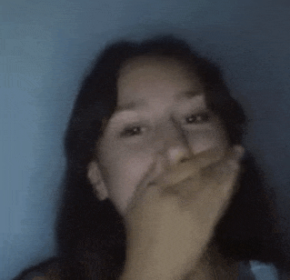 a girl is covering her mouth with her hand .