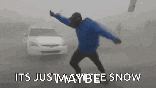 a man in a blue jacket is dancing in front of a car in the fog .