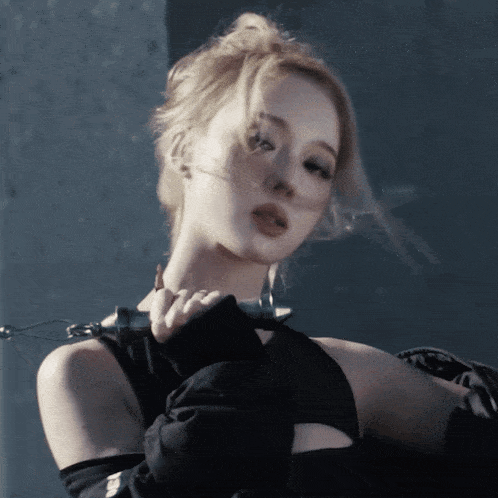 a woman wearing a black top and gloves holds a chain around her neck