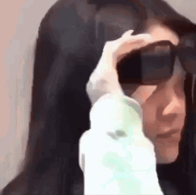a close up of a woman wearing sunglasses and a white shirt .