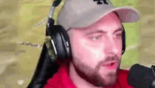 a man with a beard is wearing headphones and a baseball cap .