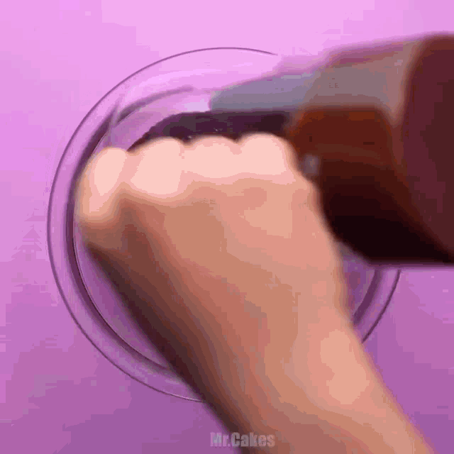 a close up of a person 's hand on a purple surface with the words mrcakes on the bottom right