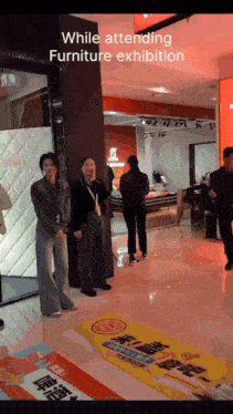 a group of people are standing in a store while attending a furniture exhibit