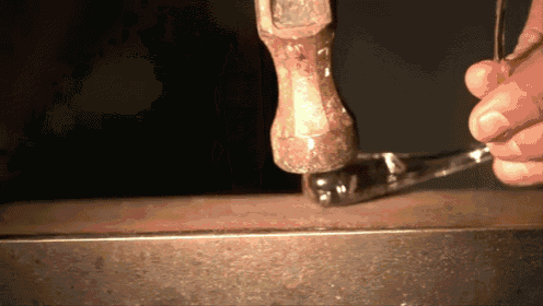 a person is using a hammer to hammer a piece of metal