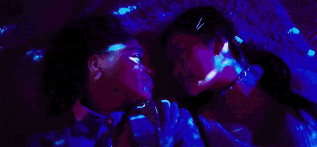 a man and a woman are kissing in a dark room with glow in the dark lights .