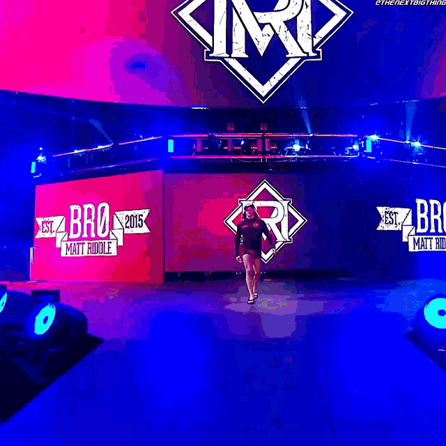 a man is walking on a stage with a matt riddle sign behind him
