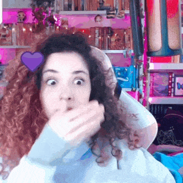 a woman with curly hair and a purple heart on her head looks surprised