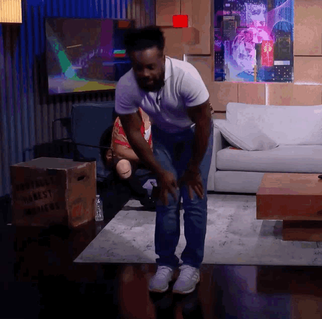 a man dancing in a living room with a box that says honest mothers on it