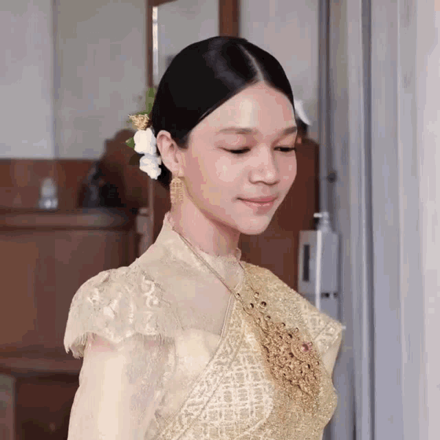 a woman with a flower in her hair wearing a gold dress