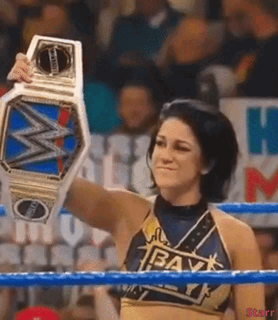 a woman in a wrestling ring holds up a heavyweight championship belt .