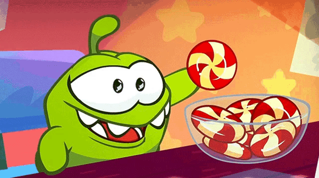 a green cartoon character is holding a red and yellow lollipop next to a bowl of candy