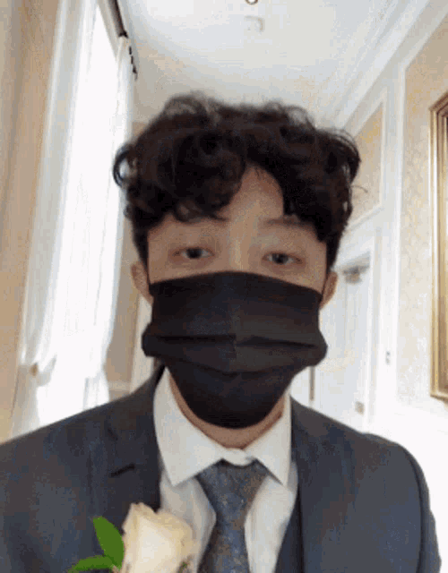 a man in a suit and tie wearing a black mask