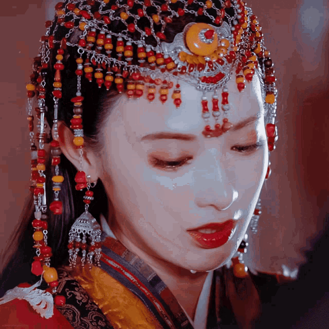 a close up of a woman 's face wearing a headpiece with beads