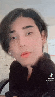 a close up of a person 's face with a black shirt and earrings .