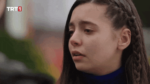 a close up of a girl 's face with a trt1 logo in the background