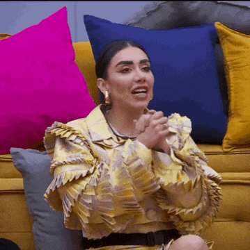 a woman sitting on a yellow couch with pillows