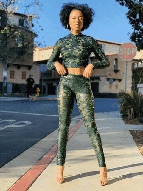 a woman is standing on a sidewalk next to a stop sign
